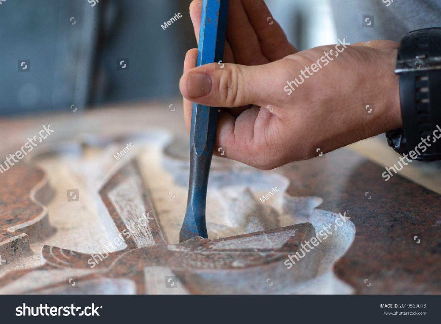 stock-photo-caucasian-man-hands-bushhammered-a-tombstone-in-a-workshop-work-concept-2019563018